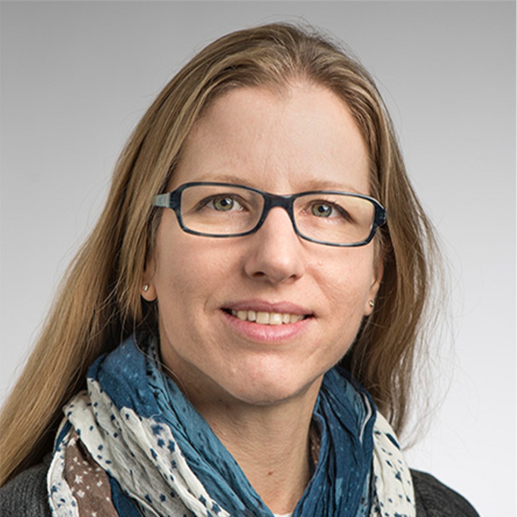 Headshot of Michal Bassani-Sternberg. She is has long blonde hair and light skin. She is wearing dark rectangular frame glasses and a blue, white, and beige scarf.