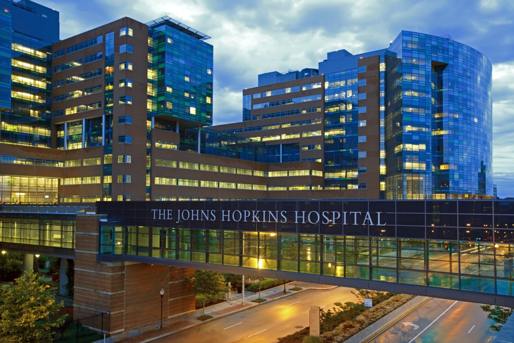 Photograph of Johns Hopkins Hospital at dusk on a cloudy day. The building is illuminate in in lights.